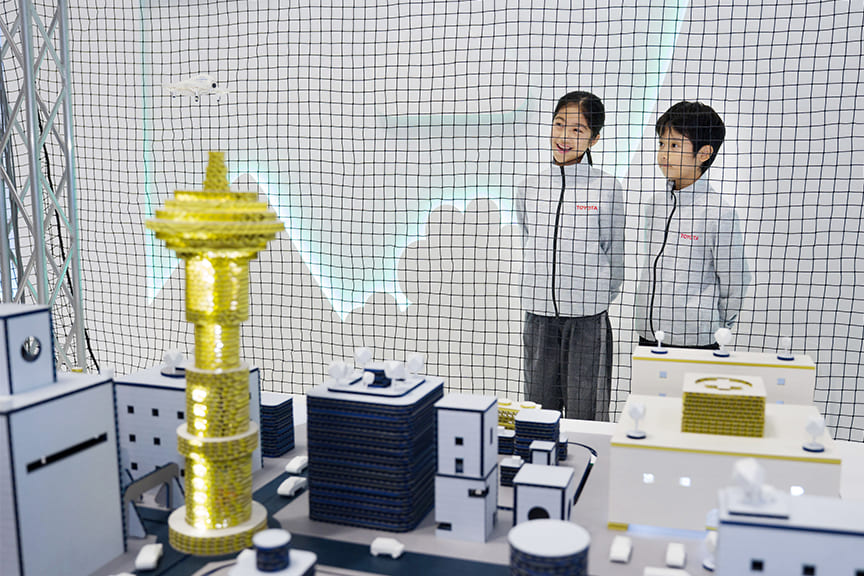 街のジオラマの前に立つ子供たち